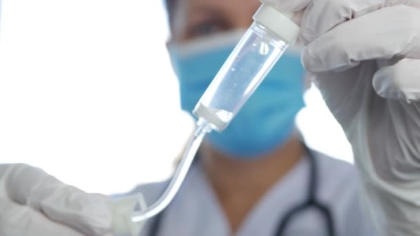 Médico con máscara protectora y guantes de cirugía en la sala de urgencias del hospital que comprueba la perfusión intravenosa — Vídeos de Stock