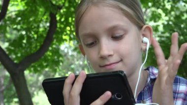 Çocuk parkta oyun parkında tablet oynuyor, Kız İnternet 'i tarıyor, Doğada Bench Açıkhava' da çocuk telefonu kullanıyor