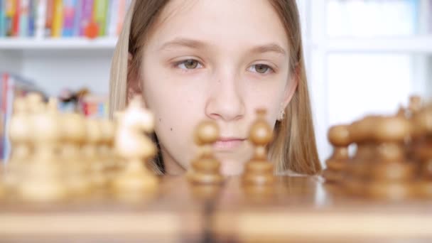 Enfant jouant aux échecs dans la bibliothèque, enfant pratiquant, apprenant, adolescente blonde étudiant le jeu de cerveau — Video