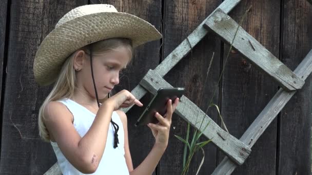 Kind spielt Tablet im Freien, Cowboy-Kind surft Smartphone, rustikales junges Mädchen sucht Internet auf dem Land im Hof — Stockvideo
