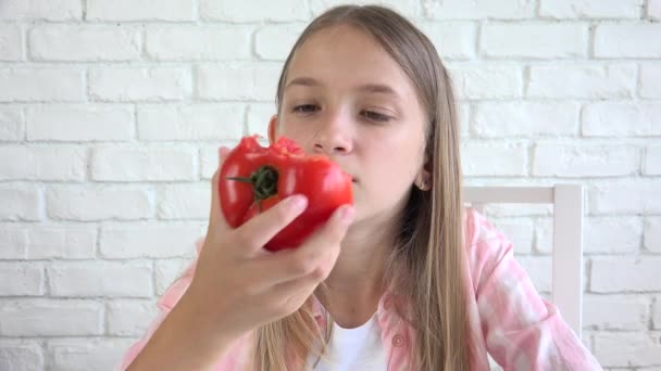 Kind eet tomaat, kind eet fruit, jong meisje proeft groenten bij het ontbijt in de keuken — Stockvideo