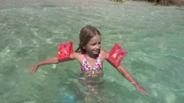 Çocuk sahilde deniz suyunda oynuyor, Çocuk sahilde oynuyor, Yüzen Şamandıralı Sarışın Kız Sahilde Dalgaların tadını çıkarıyor