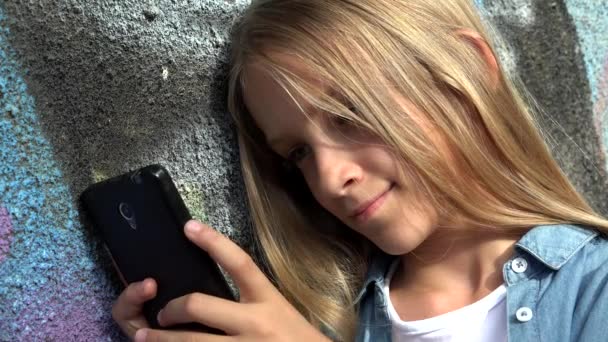 Παιδί που παίζει στο Smartphone στο Πάρκο, Παιδί που περιηγείται στο Internet στο Smart Phone, Ξανθιά έφηβος κορίτσι πληκτρολογώντας μηνύματα Μιλώντας στη συσκευή — Αρχείο Βίντεο