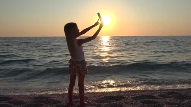 Kid Brincando na Praia, Criança Tirando Selfie Via Smartphone no Pôr do Sol, Garota Jogando Tablet no Mar, Crianças em Férias de Verão — Vídeo de Stock