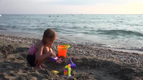 Gyerek épület vár strandon naplementekor, gyermek játszik homokban a tengerparton, szőke lány játszik a tenger, a gyerekek a nyári vakáció — Stock videók