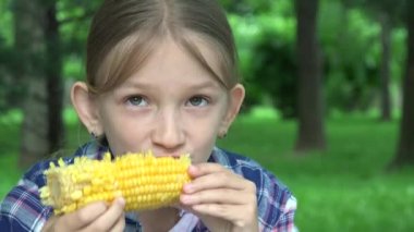 Çocuk parkta haşlanmış mısır yiyor, Aç Kız sağlıklı abur cubur yiyor, Genç Sarışın Çocuk doğada dinleniyor.