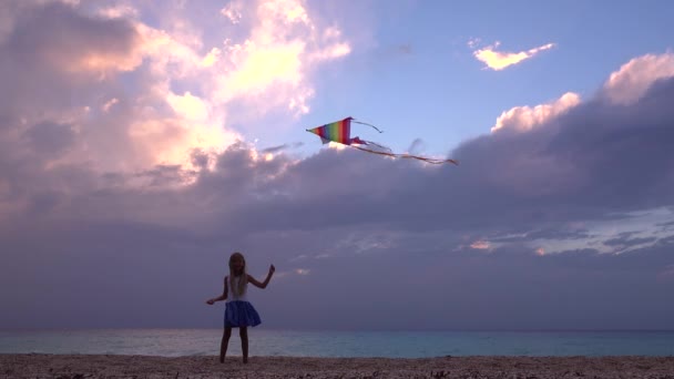 Niño jugando en la playa en la orilla del mar, Kid Flying Kite al atardecer en el océano, Chica en la costa en vacaciones de verano Sea Waves al atardecer — Vídeo de stock