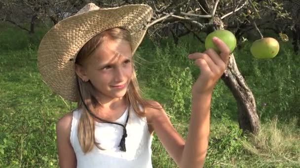 Παιδί τρώει μήλο, παιδί στον οπωρώνα, παιδί δοκιμάζει φρούτα στο δέντρο, αγρότης ξανθιά κοπέλα στο χωριό στην ύπαιθρο — Αρχείο Βίντεο
