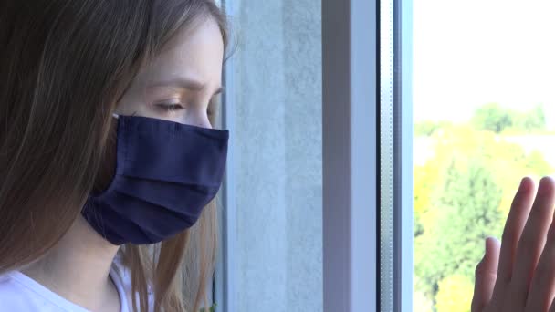 Ziek kind dragen beschermende masker in Coronavirus pandemie, triest kind op zoek naar venster, ongelukkig verveeld meisje in Covid-19 Crisis — Stockvideo