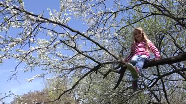 Lachendes Kind klettert auf Frühlingsblütenbaum im Park, Kind lächelt bei Blumen, fröhliches junges Mädchenporträt lacht — Stockvideo