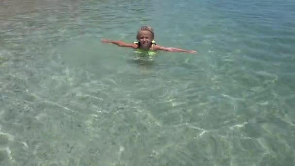 Barnet leker i havet vatten på stranden, Kid med simning liv boj njuter av vågor på stranden, Flicka leker på kustlinjen — Stockvideo