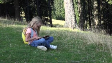 Çocuk dağlarda kampta çayırda tablet oynuyor, Ormanda çocuk akıllı telefonları kullanıyor, kız dışarıda parkta oyun oynuyor.