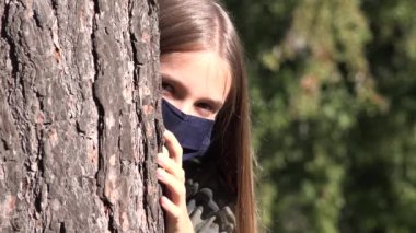 Koronavirüs salgını nedeniyle koruyucu maske takan hasta çocuk, parkta tecrit edilmiş üzgün kız, oynamayan mutsuz genç kız.