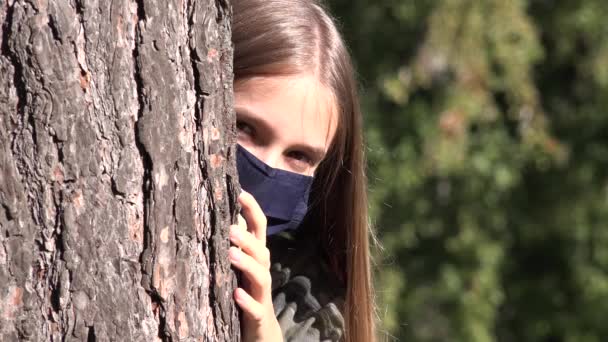 Больной ребенок в защитной маске из-за пандемии коронавируса, грустная девочка, изолированная в парке, скучающая несчастная девочка-подросток, не играющая — стоковое видео