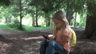Çocuk dağlarda kampta çayırda tablet oynuyor, Ormanda çocuk akıllı telefonları kullanıyor, kız dışarıda parkta oyun oynuyor.
