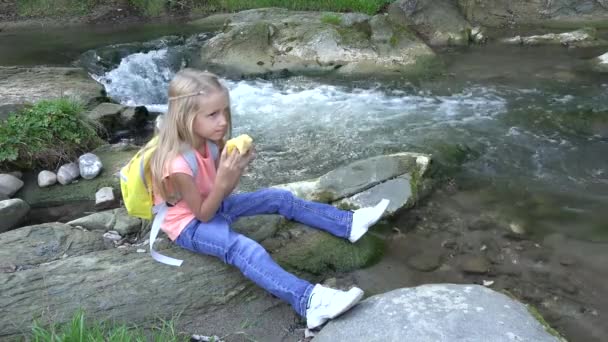 Дитина їсть яблука річкою, дитина в кемпінгу в горах Перегляд, дівчина їсть фрукти на відкритому повітрі в природі, охорона здоров'я дітей — стокове відео