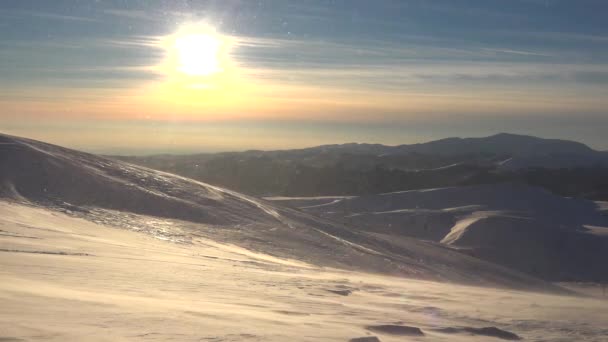 Ventisca en las montañas en invierno, nieve soplada por el viento en la estación de esquí, vista alpina, paisaje de nevadas al atardecer — Vídeos de Stock