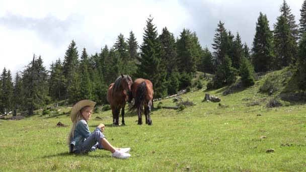 Fazendeiro criança pastoreio cavalos, Cowboy Kid com animais no prado, pradaria rústica menina brincando ao ar livre em montanhas — Vídeo de Stock
