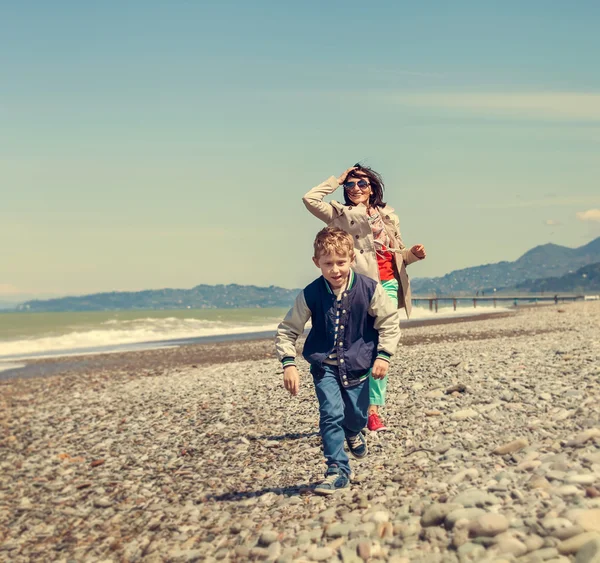 Mały syn z matka biegnie razem na wybrzeżu Morza — Zdjęcie stockowe