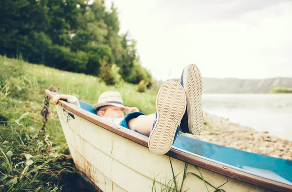 Jongen liggen in oude boot — Stockfoto