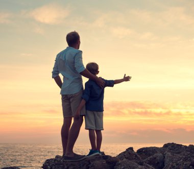 Baba ve oğul günbatımı üzerinde seyir 