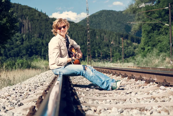 Oung homem com guitarra na Ferroviária — Fotografia de Stock