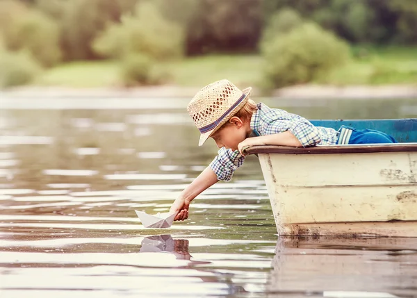 Маленький мальчик запуска бумага судно от старой лодке — стоковое фото