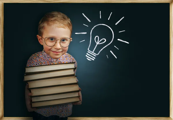 Niño con libros cerca de pizarra de la escuela —  Fotos de Stock