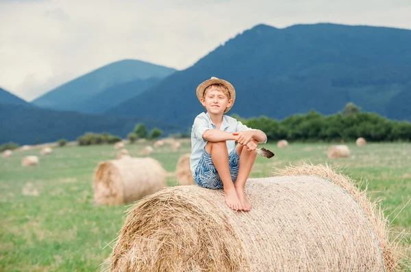 Boy sits on haystack — Stock Photo, Image