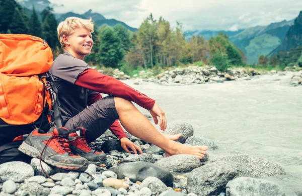 Uomo riposo sulla riva del fiume di montagna — Foto Stock