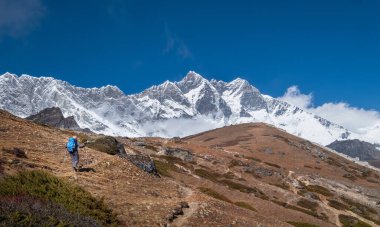Lhotse Ana Kampı 'na giden sırıkla yalnız gezen genç bir kadın. Tehlikeli Lhotse Güney Surat, 8516 metre yükseklikte ve mavi gökyüzü arka planda. Aktif insanlar, Nepal konseptinde aşırı tırmanma.