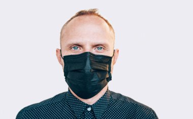 Kameraya bakarken COVID-19 salgını sırasında siyah yüz maskesi takan bir adamın portresi. Kendini koruma ve virüs yayma konsept görüntü yayma 