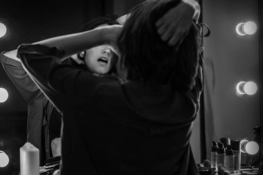 Saçlarını dalgalandırırken aynadaki yansımasına bakan baştan çıkarıcı kadının şehvetli, sade bir portresi. İnsani duygular veya moda konsepti.