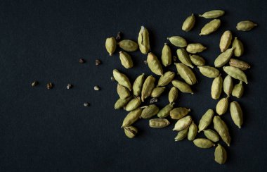 Kakule podlarının ve tohumların Matt 'in siyah arka planına yakın fotoğrafını çek. Hint ve Sri Lanka mutfağında çok popülerdir..