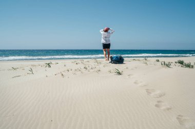 Patara kumullarında sırt çantalı bir kadın Lycian Yolu yürüyüş sırasında rüzgarlı Akdeniz 'in tadını çıkarıyor. Letoon yakınlarındaki ünlü Likya Yolu Türk rotası. Etkin insanlar tatil konsepti imajı