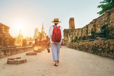 Ayutthaya Wat Phra Ram 'ın Tayland' daki antik harabelerinde fotoğraf makinesiyle yürüyen genç bir kadın turist. Tarih, turizm, gezi konsepti.