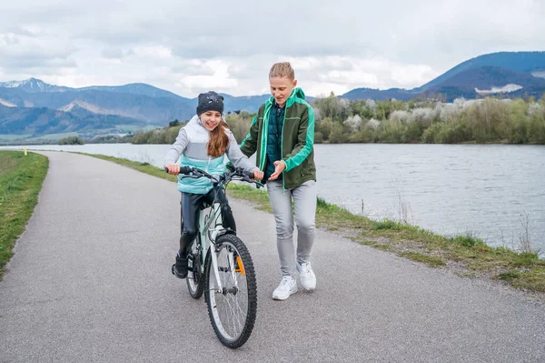 快乐的户外童年概念形象 哥哥小心翼翼地跟着姐姐帮助她 教她骑自行车的第一步 — 图库照片