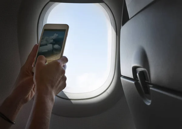 スマートフォンを使って雲や航空機のエンジンを撮影する女性 飛行機の航空輸送コンセプトイメージによるアクティブな旅行や飛行 — ストック写真
