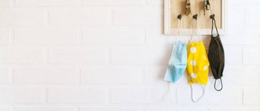 Anahtar düzenleyici kancadaki ağaç koruyucu maskeler ev koridorundaki beyaz arka plan tuğla duvara takılmış. COVID-19 pandemik konsept arkaplan görüntüsü sırasında sağlık hizmeti kavramı. 