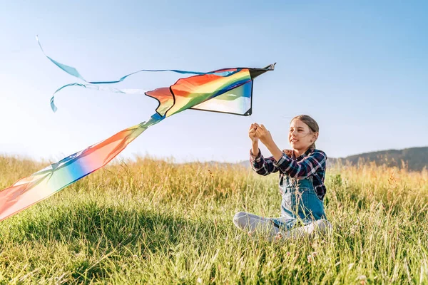9Yo Gülümseyen Kız Çimlerin Üzerinde Oturuyor Renkli Gökkuşağı Uçurtma Oyuncağını — Stok fotoğraf
