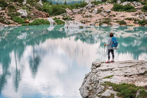 バックパックとトレッキングポールを持つバックパッカーの女性は イタリアのドロマイト山脈を歩く山の中でターコイズブルーのLago Sorapiss 1925Mの高さの湖の景色を楽しんでいます 自然概念の活動家 — ストック写真