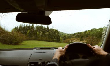 Yağmurlu bir günde, dağ yeşil orman kır yolunda modern bir off-road sürücüsü sağ elle RHD araba kullanıyor. POV arabanın ön camına bakıyor. Güvenli otomatik sürüş konsepti.