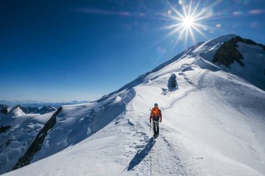 Mont Blanc (Monte Bianco) zirvesinden önce 4808 metre yükseliyor. Ekip baltayla tırmanırken yüksek rakımlı dağcı kıyafetleri giymiş sırt çantalı adam mavi gökyüzü karlı yamaçlarda yürüyordu..