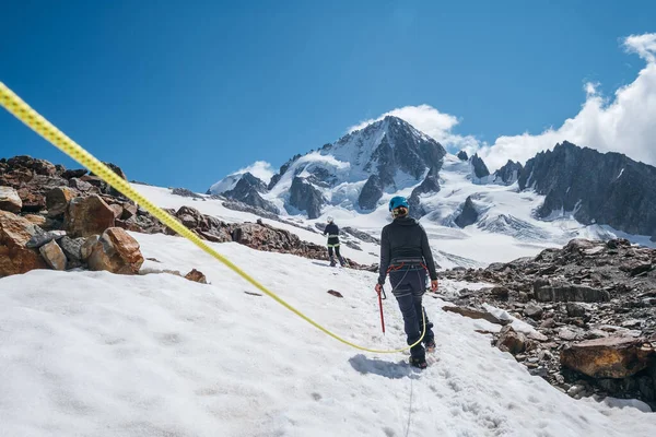登山着を着た2人の女性ロープチームメンバー氷の斧で氷の斜面を登るハーネスと近くの前景にダイナミックなロープで歩く登山服に身を包んだ — ストック写真