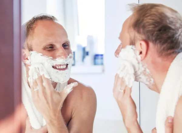 Shaving man near the bathroom mirror — Stock Photo, Image