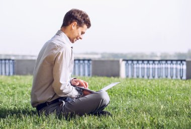 çimenlerin üstünde Laptop ile çalışan adam