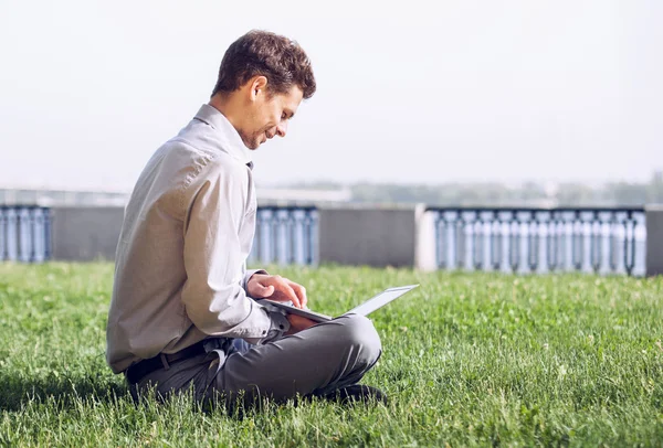 Człowiek pracy z laptopem na trawniku — Zdjęcie stockowe