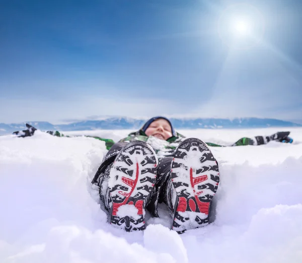 Мальчик, лежащий в глубоком снегу — стоковое фото