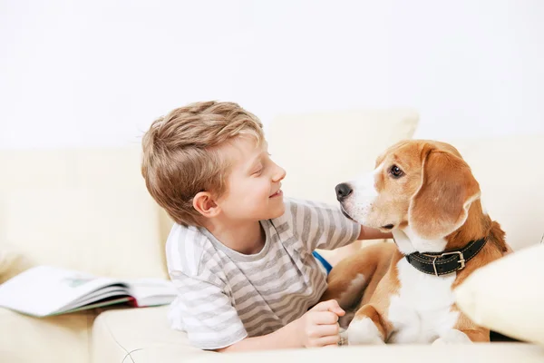Мальчик и собака, лежащая на диване — стоковое фото