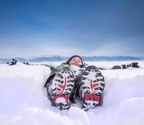 深い雪の中で横になっている男の子 — ストック写真